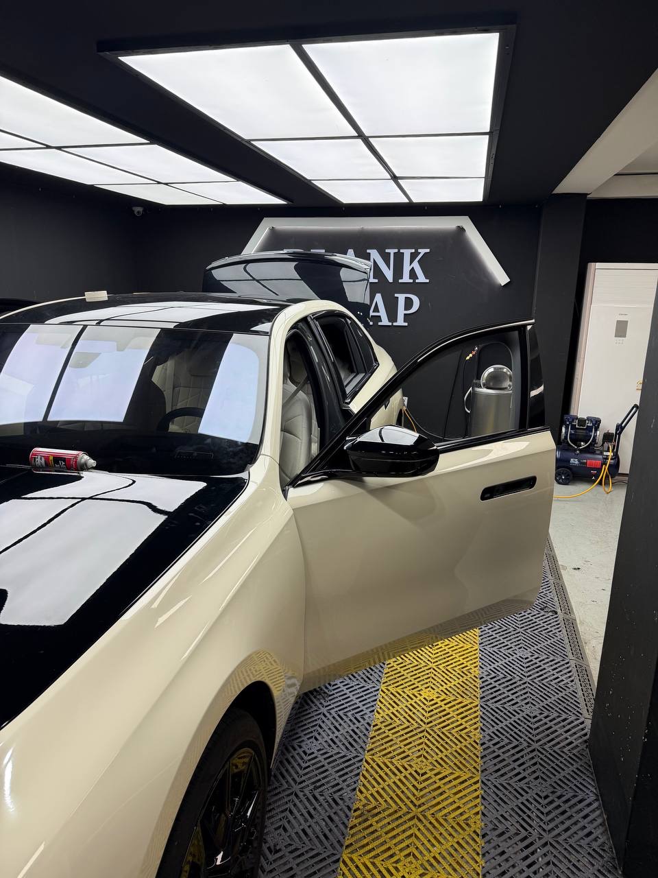 BLANK WRAP 간판이 걸린 블랭크랩 작업장에서 아이보리 · 블랙 투톤으로 랩핑 중인 BMW i7 M70