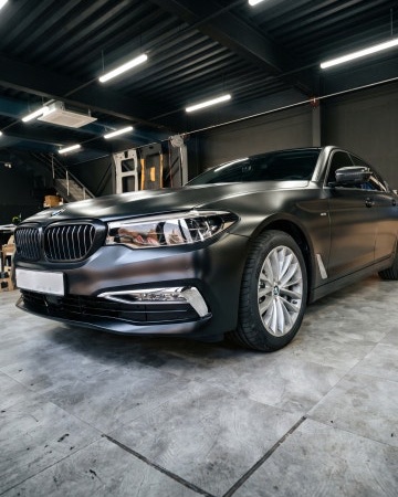 시공 후: 사틴 블랙으로 랩핑하고 루프를 유광 블랙으로 감싼 BMW 5시리즈 앞모습