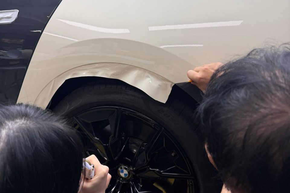 작업자들이 휠 아치 둘레의 필름을 정리하는 모습